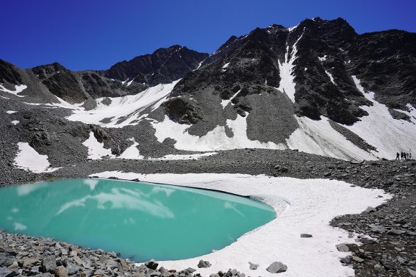 Foto eines türkisen Gletschersees mit Bergspitze im Hintergrund.