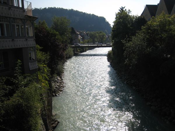 Fluss Ill seitlich gruen bewaldet und im Hintergrund eine Bruecke