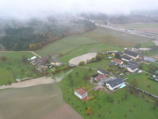 Dorf, umliegende gruene Flaechen sind ueberflutet