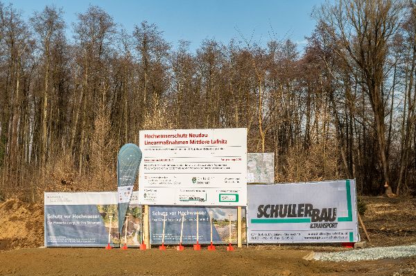 Bautafel mit der Aufschrift  Hochwasserschutz Neudau , Linearmaßnahmen Mittlere Lafnitz und verschiedene Werbetafeln