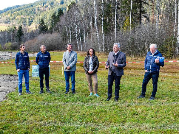 fuenf Personen im Gespraech im Hintergrund Landschaft mit Nadelwald und herbstlichen Farben