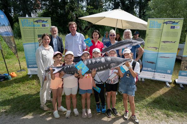 Festgäste bei der Station LIFE Boat 4 Sturgeon, vor ihnen stehen Kinder, sie halten zwei Stofftierstöre in den Händen