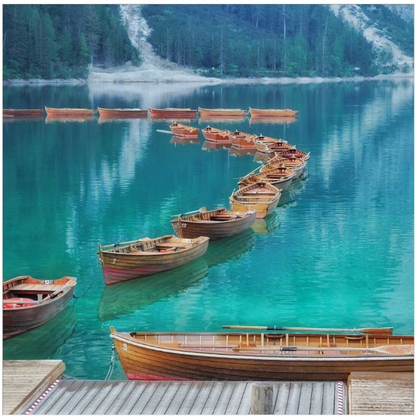 Auf dem Bild ist ein Bergsee mit einigen kleinen Booten zu sehen
