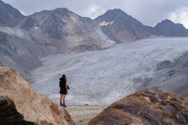 Frau blickt auf einen Gletscher im Gebirge.