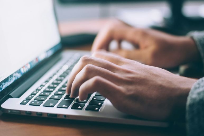 Hände auf Tastatur eines Laptops