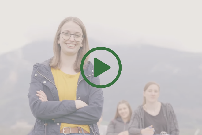 A young woman crosses her arms; next to her, a green play button can be seen.