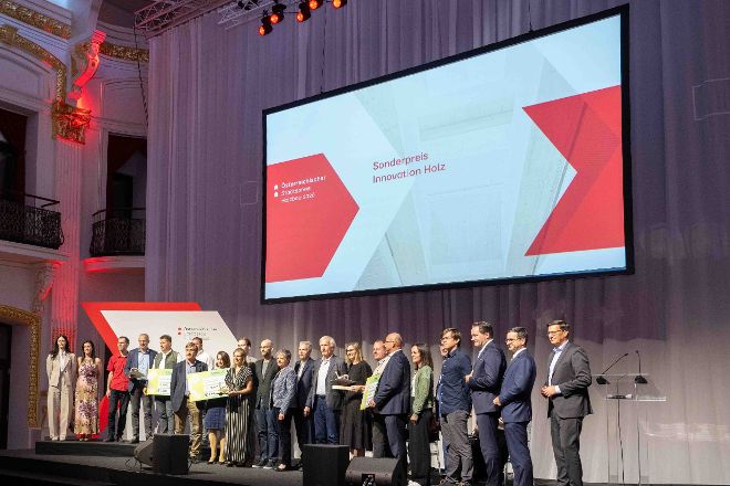 Eine Gruppe von Menschen steht auf der feierlichen Bühne der Sofiensäle - auf der Leinwand steht Sonderpreis Innovation Holz