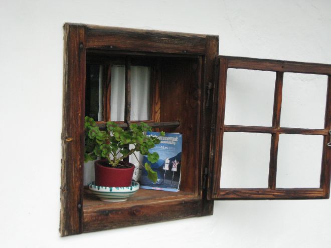 Historisches Doppelkastenfenster mit geöffnetem Außenflügel, auf Fensterbank steht Blumentopf in Keramikübertopf