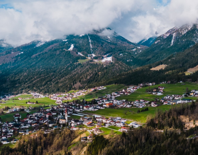 Landschaft mit Bergen im Hintergrund und einer Siedlung im Tal im Vordergrund