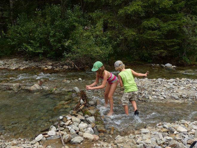 Das Foto zeigt im Wasser stehende, spielende Kinder am Bach